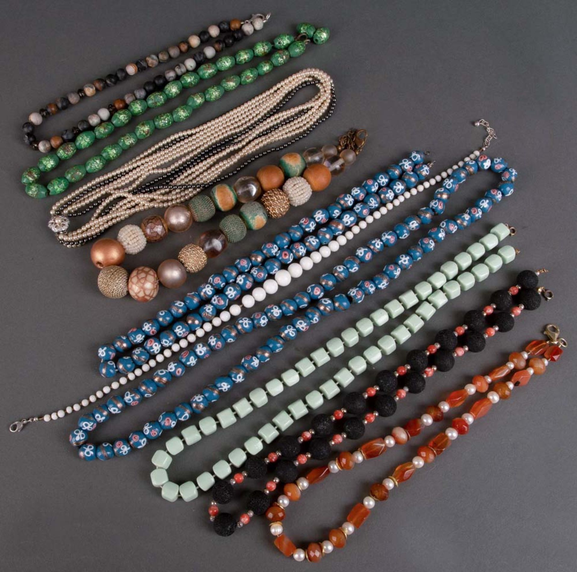 Zehn Modeschmuck-Halsketten, u.a. mit bernstein-, jade-, perlen- und quarzfarbigen Gliedern.