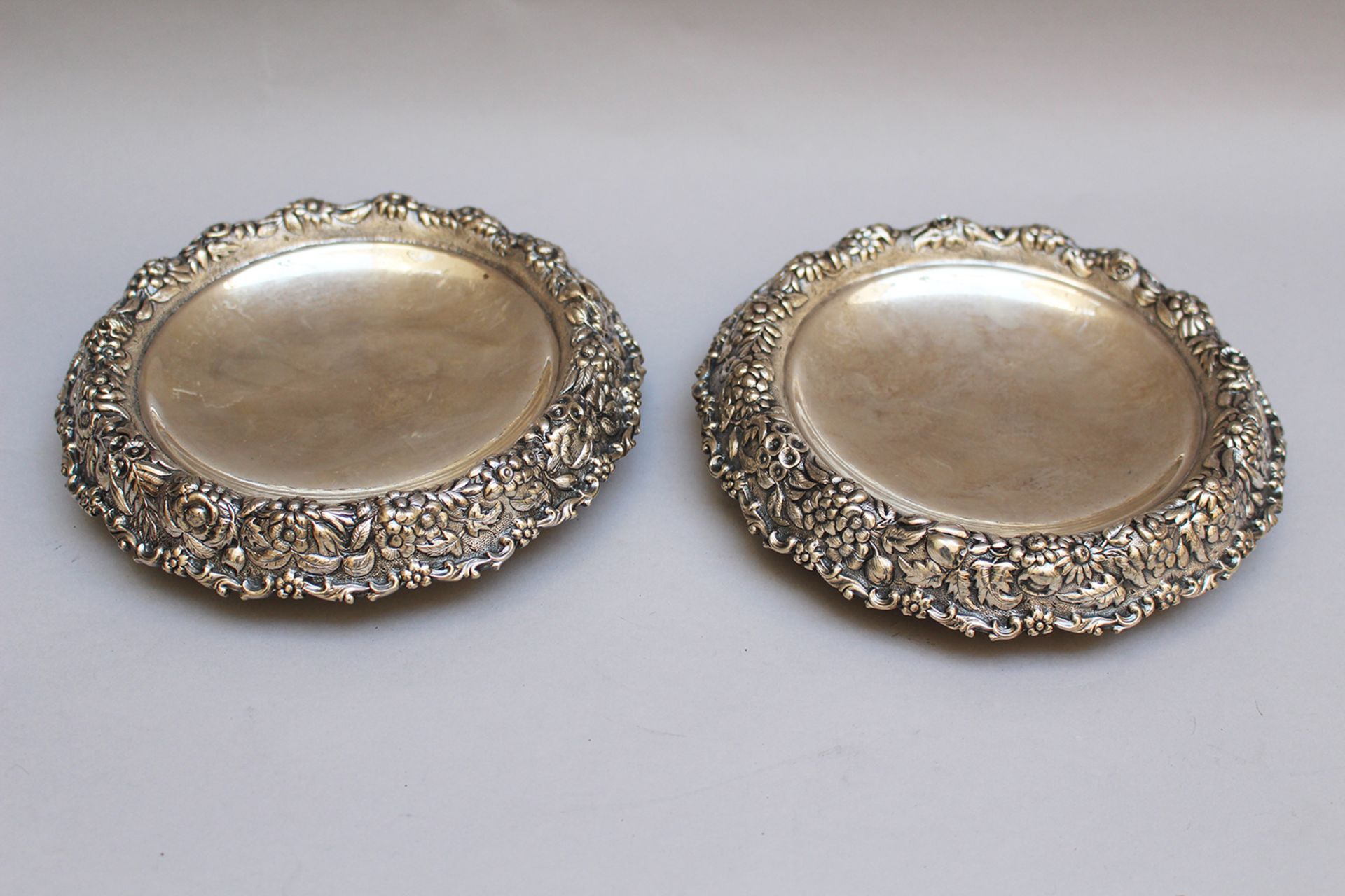Two Tiffany tazzas round shape with lowered centre surrounded by floral decorations, stamped on