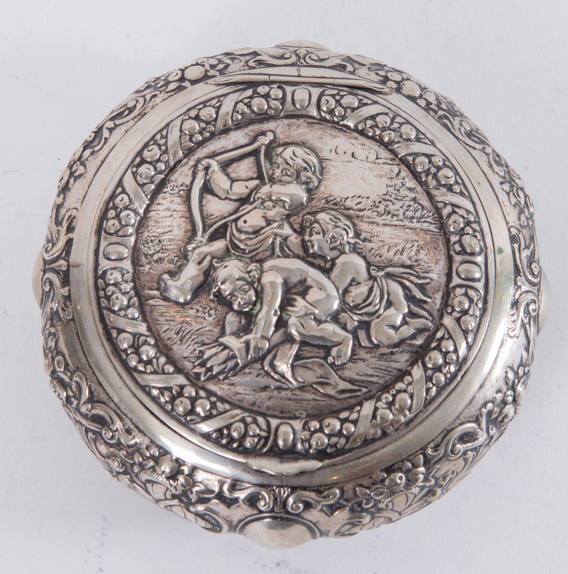 Argentiere tedesco, XX secolo. Scatola rotonda in argento 800 decorata con putti. Sotto la base reca