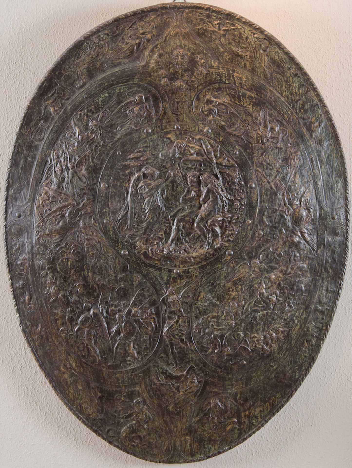 Scudo in terracotta patinata bronzo. Italia, XX secolo. Reca scena centrale raffigurante la cacciata