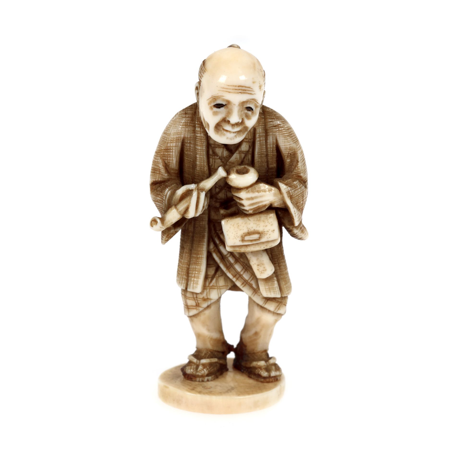Ivory Netsuke, depicting an old man preparing his pipe, signed, Japan, late 19th century