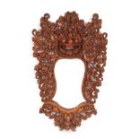Mirror with carved frame, exotic wood, depicting the protective god Rangda, decorated with plant mot
