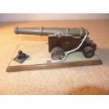 A BRASS BARRELED MODEL OF AN EARLY 19TH NAVAL CANNON, MOUNTED ON A WOODEN CARRAIGE, LENGTH OF BARREL