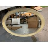 AN OVAL CREAM PAINTED WOODEN FRAMED MIRROR