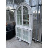 A REGENCY STYLE WHITE PAINTED CABINET WITH FOUR DOORS, ARCHED TOP, GILDED DECORATION AND MIRRORED