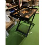 A LARGE BLACK LAQUERED BUTLER'S TRAY WITH FLORAL DECORATION ON A FOLD OUT STAND ( 50 CM X 69 CM)