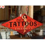 A METAL DIAMOND SHAPED 'TATTOOS AND PIERCINGS' SIGN