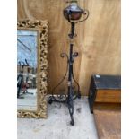 A DECORATIVE BRASS AND COPPER OIL LAMP ON A TALL DECORATIVE BLACK CAST IRON METAL STAND (H:137CM)