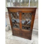 A REPRODUCTION OAK GLAZED AND LEADED BOOKCASE WITH LINENFOLD DOORS TO THE BASE, 38" WIDE