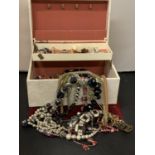 A LARGE CREAM LEATHER EFFECT JEWELLERY BOX CONTAINING A LARGE QUANTITY OF COSTUME JEWELLERY