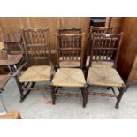 A SET OF FIVE SPINDLE BACK OAK LANCASHIRE CHAIRS WITH RUSH SEATS - FOUR DINING CHAIRS AND ONE ROCKER