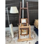 AN ARTIST'S EASEL, TWO TRESTLE STANDS, A STANDARD LAMP, A MIRROR AND TWO PRINTS