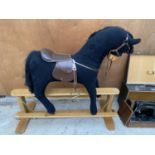 A BLACK ROCKING HORSE ON WOODEN STAND