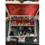 A CREAM HINGED JEWELLERY BOX CONTAINING A VARIETY OF COSTUME JEWELLERY