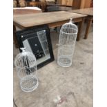 TWO WHITE BIRD CAGES OF DIFFERENT SIZES AND A DECORATIVE FRAMED MIRROR