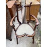 AN EDWARDIAN MAHOGANY ELBOW CHAIR WITH HEART SHAPED SEAT AND HARP STYLE BACK