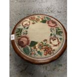 A WOODEN CIRCULAR TAPESTRY TOPPED FOOTSTOOL