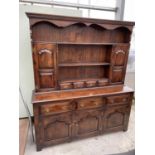 AN OAK DRESSER WITH THREE LOWER DOORS AND DRAWERS, UPPER PLATE RACK WITH TWO DOORS AND FOUR SMALL
