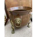 A BRASS AND COPPER CAULDRON WITH DECORATIVE CLAW FEET AND LION HEAD HANDLES