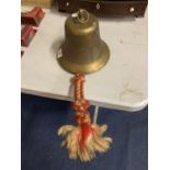 A LARGE BRASS BELL WITH ROPE