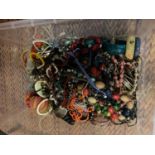 A LARGE CLEAR CONTAINER OF MIXED COSTUME JEWELLERY TO INCLUDE NECKLACES, BANGLES ETC