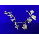 A SILVER CHARM BRACELET MARKED STERLING WITH EIGHT VARIOUS CHARMS IN A PRESENTATION BOX