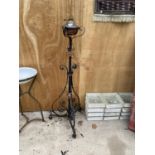 A DECORATIVE BRASS AND COPPER OIL LAMP ON A TALL DECORATIVE BLACK CAST IRON METAL STAND (H:137CM)