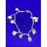 A SILVER CHARM BRACELET WITH NINE CHARMS TO INCLUDE CLOGS, FEATHERS, TURTLE, FISH, SHELL ETC