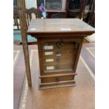 A MINIATURE OAK SAMPLE CHEST WITH GLAZED DOOR, LOWER DRAWER AND FIVE INNER DRAWERS