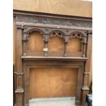 A LARGE ORNATE WOODEN FIRE SURROUND WITH DECORATIVE CARVING