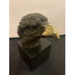 A BRONZE EAGLE HEAD ON A MARBLE BASE