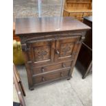 A JACOBEAN STYLE OAK TALLBOY WITH CARVED PANEL DOORS AND TWO DRAWERS TO THE BASE