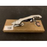 A CHROME JAGUAR CAR MASCOT ON A WOODEN PLINTH