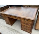 AN EDWARDIAN OAK KNEEHOLE DESK ENCLOSING TWO BANKS OF FOUR GRADUATED DRAWERS, CENTRAL DRAWER AND