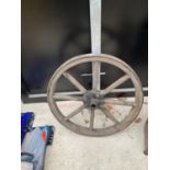 A VINTAGE WOODEN CART WHEEL WITH METAL OUTER BAND