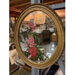 AN OVAL GILT FRAMED MIRROR WITH RED ROSE DESIGN
