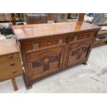 A WALNUT ART NOUVEAU SIDEBAORD ENCLOSING TWO DRAWERS AND CUPBAORDS WITH CARVED PANEL, 60" WIDE