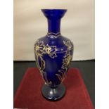 A BLUE GLASS URN WITH GOLD RELIEF FLOWER PATTERN (HEIGHT 26CM)