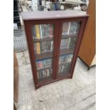 A MAHOGANY EFFECT BOOK/DVD CABINET ENCLOSING APPROX 150 DVD'S, 30" WIDE