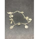 A SILVER CHARM BRACELET WITH NINE CHARMS TO INCLUDE CLOGS, FEATHERS, TURTLE, FISH, SHELL ETC