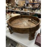 A VERY LARGE HEAVILY CARVED 19TH CENTURY INDIAN FOOD BOWL/TABLE ON FOUR LEGS AND A PAIR OF WOODEN