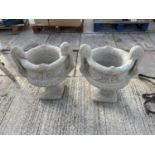 A PAIR OF STONE EFFECT GARDEN URN PLANTERS WITH DECORATIVE DETAIL ON A PEDASTEL BASE