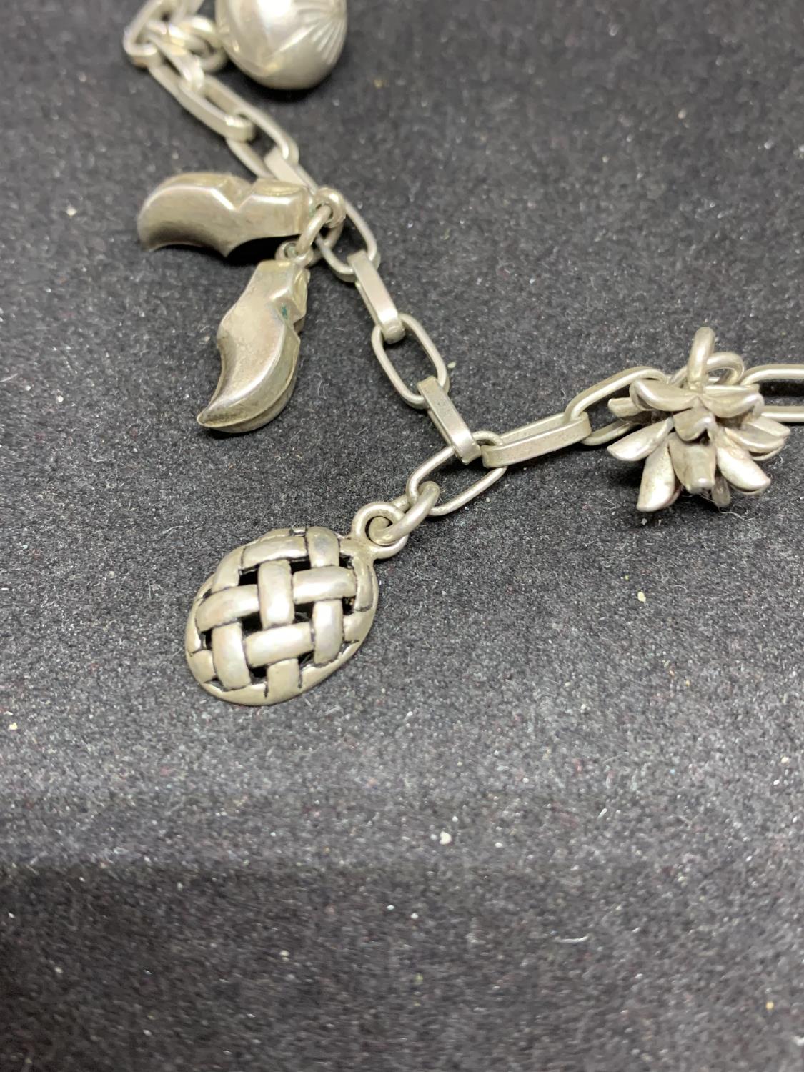 A SILVER CHARM BRACELET WITH NINE CHARMS TO INCLUDE CLOGS, FEATHERS, TURTLE, FISH, SHELL ETC - Image 2 of 4