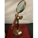 A BRASS AND WOOD MAGNIFYING GLASS ON STAND