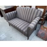 AN EDWARDIAN SPRUNG AND UPHOLSTERED SETTEE ON TAPERED LEGS WITH BRASS CASTORS