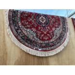 AN OVAL RED PATTERNED RUG