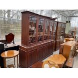 A REGENCY STYLE ASTRAGAL GLAZED FOUR DOOR BOOKCASE ON BASE, ENCLOSING FOUR FRIEZE DRAWERS AND FOUR