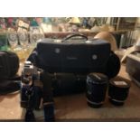 AN OLYMPUS OM 20 SELF TIMER CAMERA AND THREE TAMRON LENSES IN A CARRY CASE