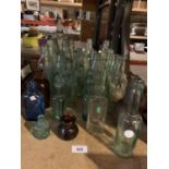 A LARGE ASSORTMENT OF VINTAGE GLASS BOTTLES TO ALSO INCLUDE A GLASS SODA SYPHON