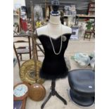 AN ORNATE VELOUR HEIGHT ADJUSTABLE FEMALE MANNEQUIN WITH FEATHER AND BEAD DETAILING AROUND THE HEM